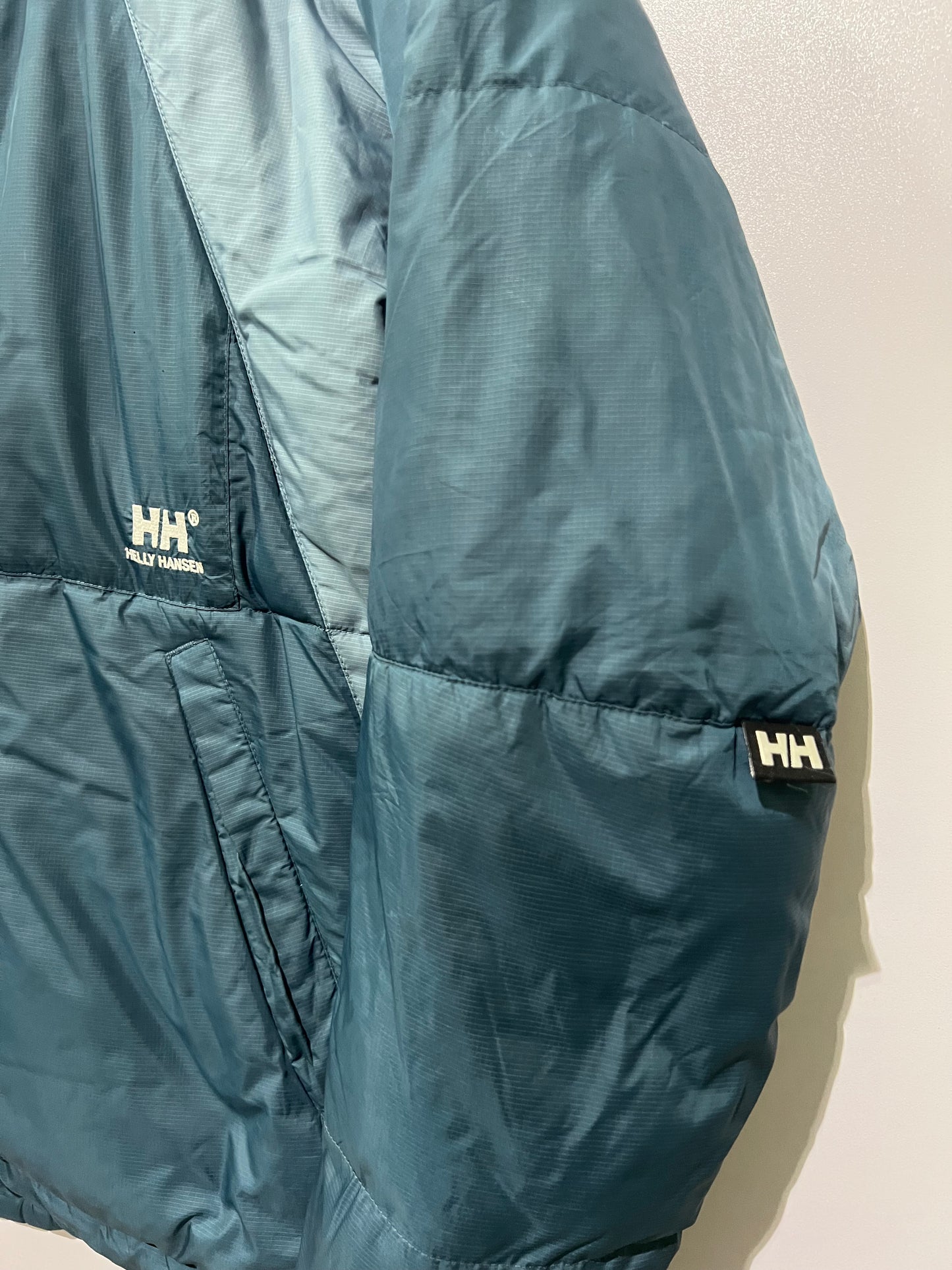vintage teal Helly Hansen puffer jacket features a prominently embroidered logo