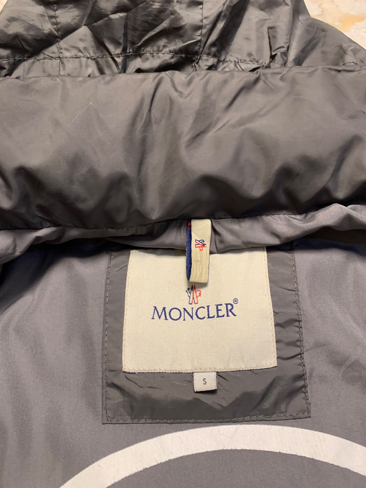 Moncler logo patch on the left sleeve, resembling a Moncler down jacket. [1]